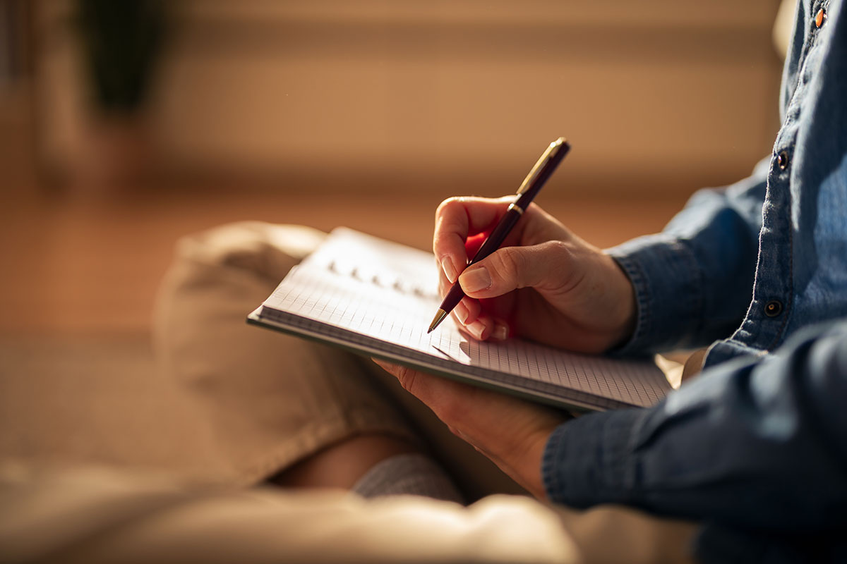 man writing on notebook